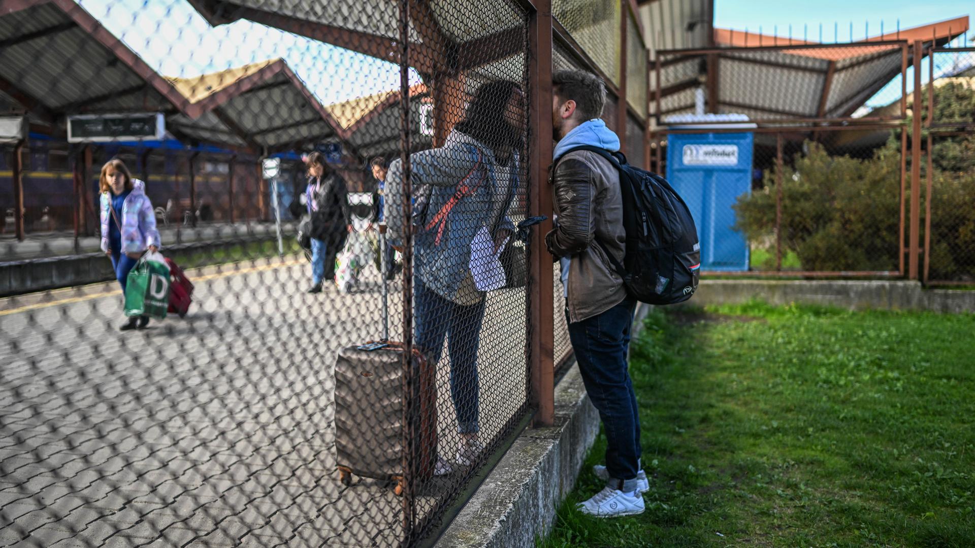 A couple kisses through a fence as she boards a train toward Kyiv at Przemysl train station on Oct. 6, 2022, Przemysl, Poland.