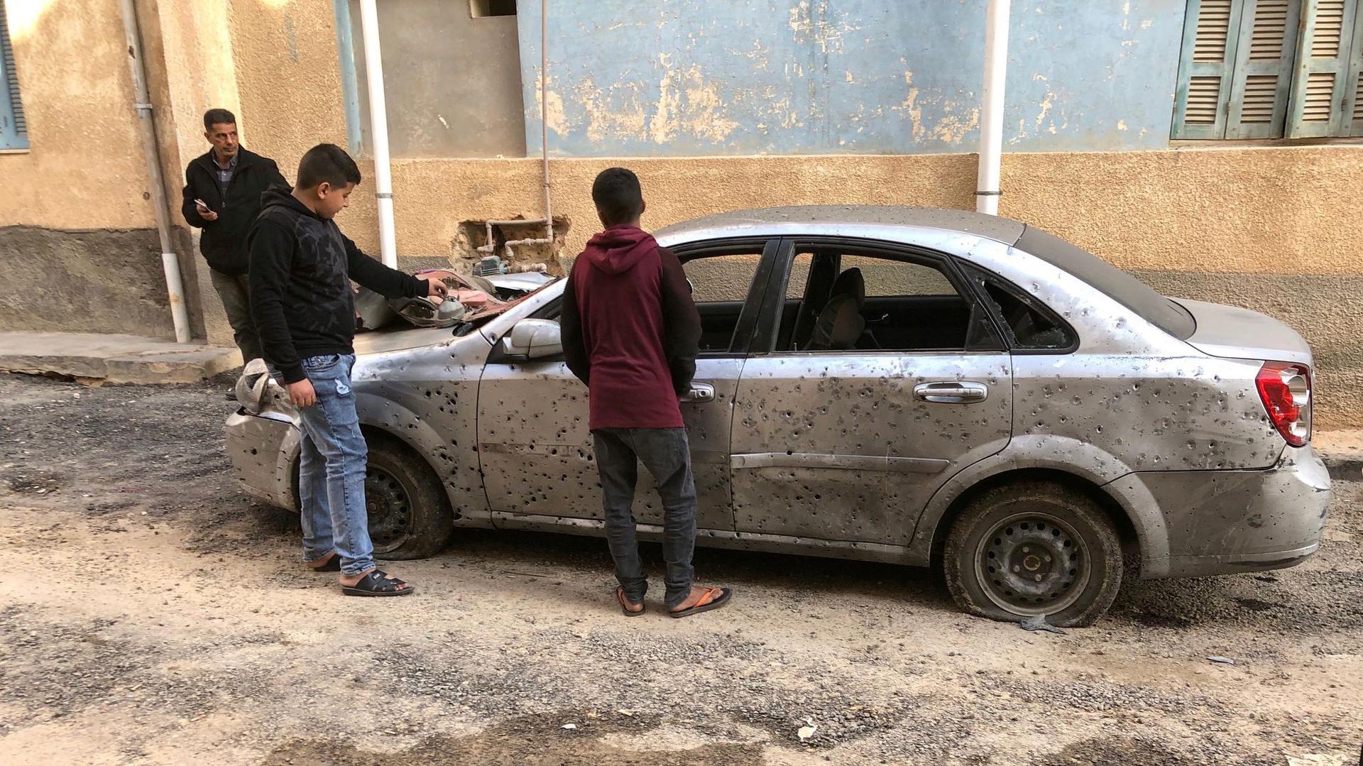 Libyan boys check a damaged car after a shell fell on a residential area at Hadba al-Badri district, in Tripoli, Libya, Jan. 28, 2020.