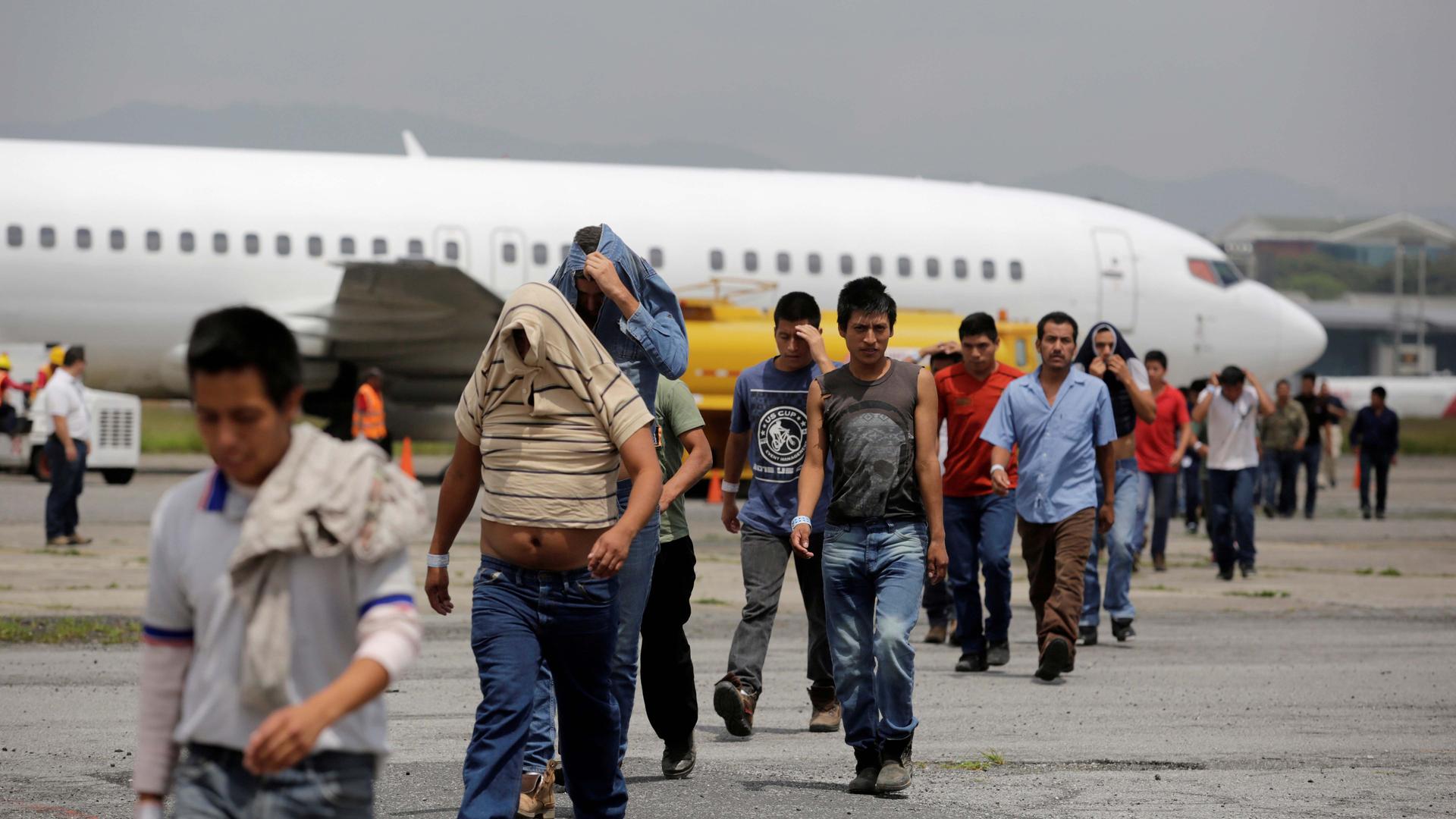 Deportees cross the tarmac after arriving on an immigration flight from the US at La Aurora international airport in Guatemala City, Guatemala, on Sept. 2, 2016.