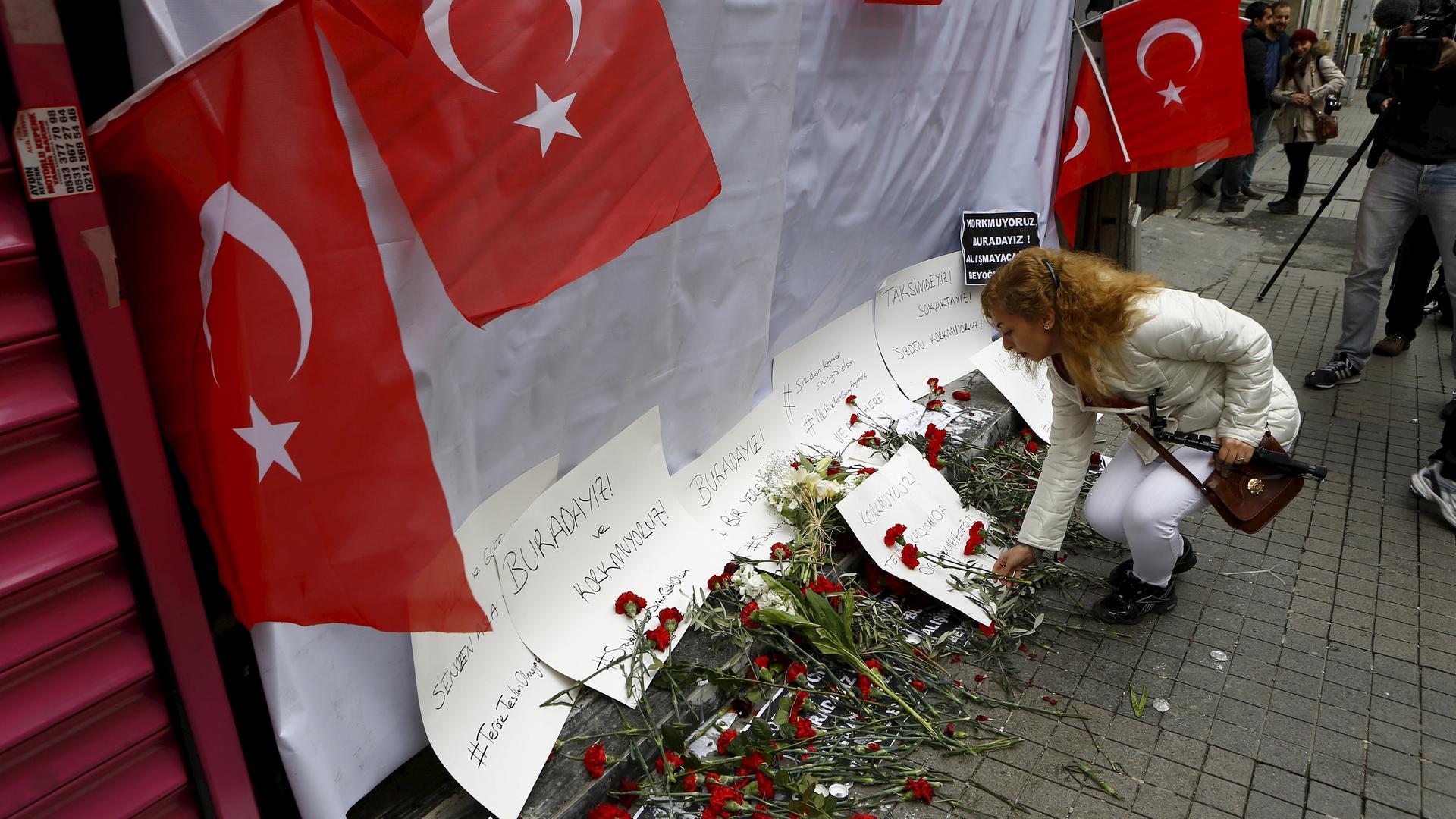 A woman places carnations at the scene of a suicide bombing at Istiklal Street, a major shopping and tourist district, in central Istanbul, Turkey.