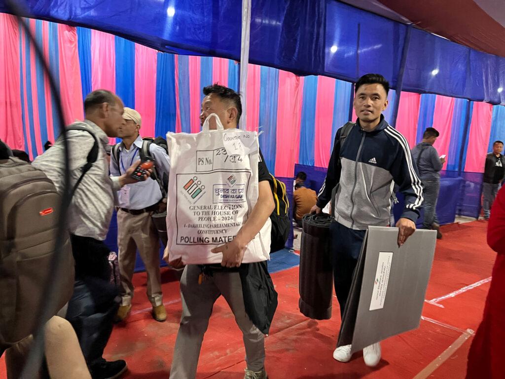 Polling officials hand out electronic voting machines, paperwork and other material to polling personnel at an election distribution center in Darjeeling.
