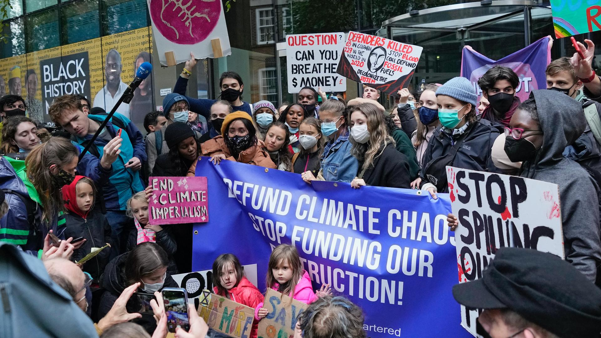 Climate activist Greta Thunberg, center, demonstrates with others in front of the Standard and Chartered Bank during a climate protest in London, Oct. 29, 2021. People were protesting in London ahead of the 26th UN Climate Change Conference (COP26), which