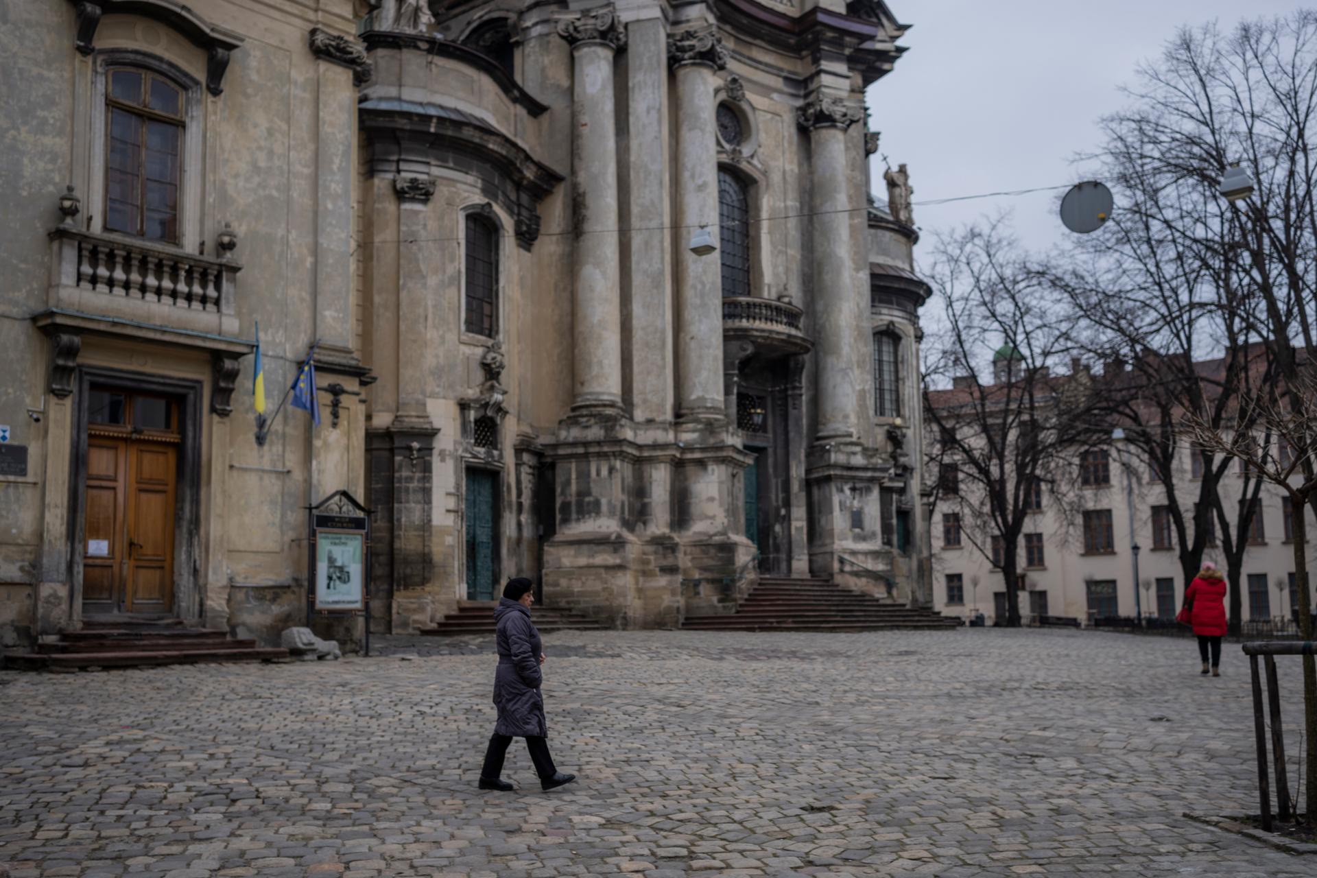A woman walks past the Museum of the History of Religion in Lviv, western Ukraine, March 4, 2022. Workers are assembling metal containers in the patio at the museum to safely store the remaining items before placing them in basements in case the Russian i
