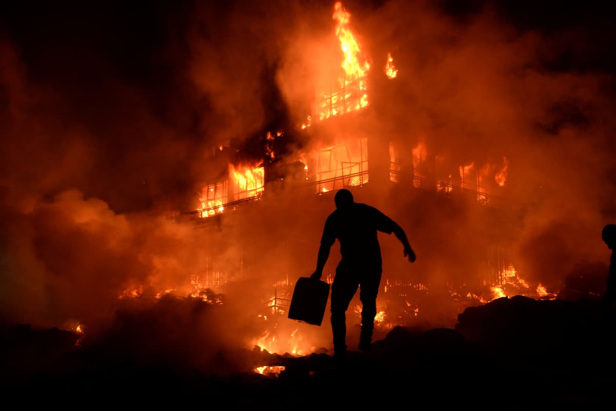 A shop owner carries a water container as he attempts to extinguish a raging fire at the central market in Mazar-i-Sharif, Afghanistan in November 2014.