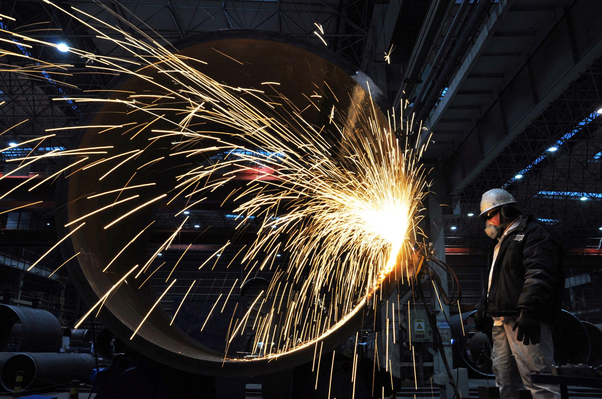 Sparks fly as a worker of China National Offshore Oil Co. cuts steel.