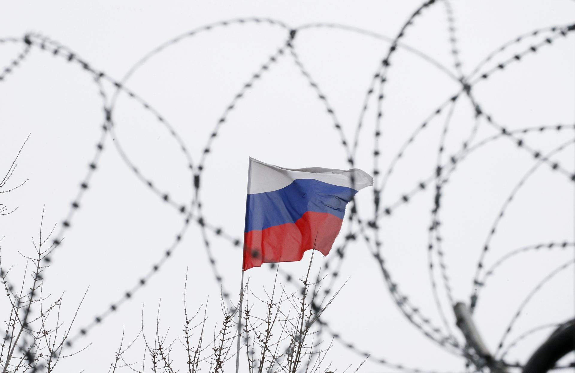 The Russian flag is seen through barbed wire as it flies on the roof of the Russian embassy in Kiev, Ukraine, March 26, 2018.