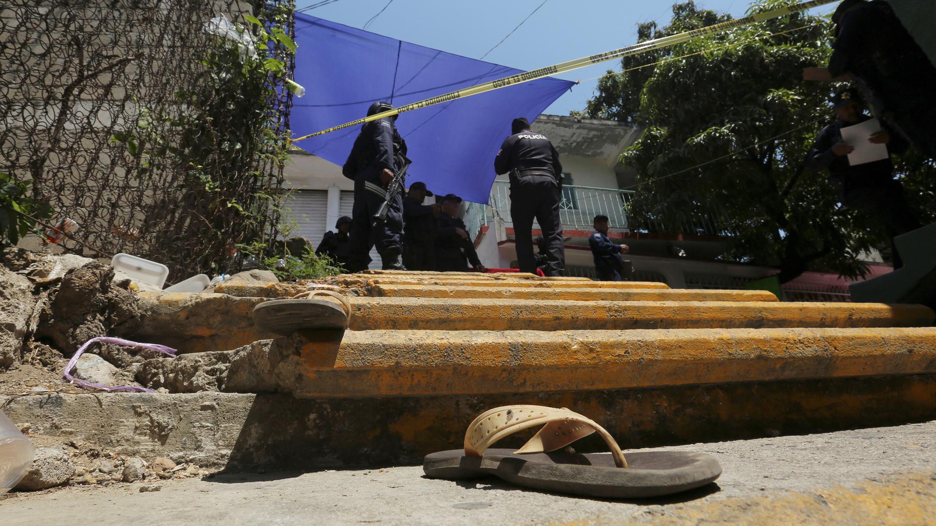 A pair of sandals are pictured near on the steps leading up to a crime scene with officials working in Acapulco.