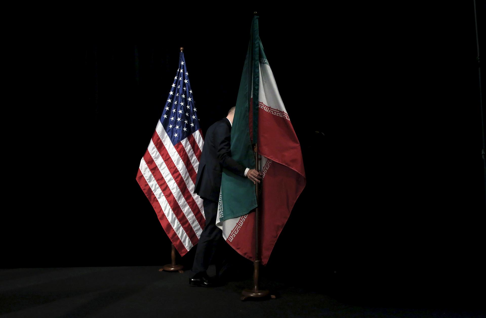 A staff member removes the Iranian flag from the stage at the Vienna International Center in Austria.