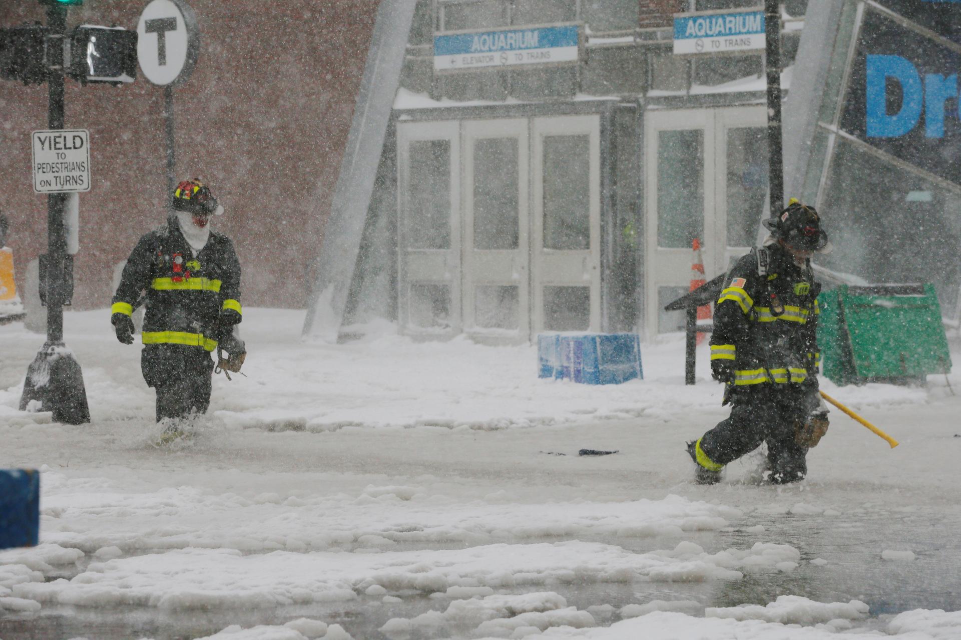 Boston firefighters wade through a street flooded from tidal surge during Storm Grayson, January 4, 2018.