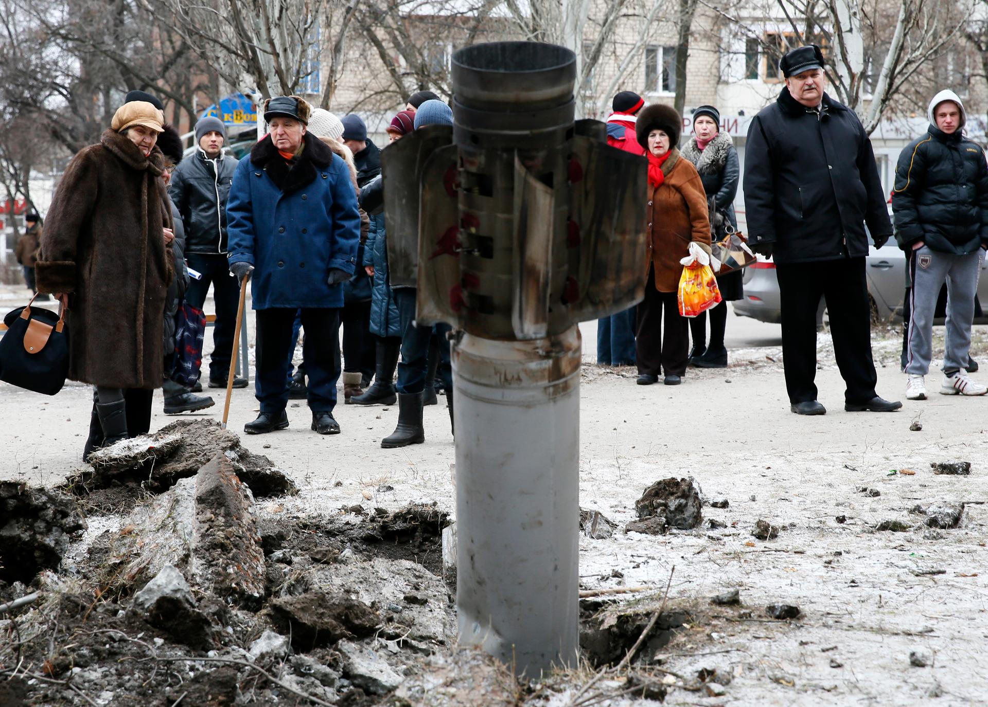 People look at the remains of a rocket shell on a street in the town of Kramatorsk, eastern Ukraine February 10, 2015.