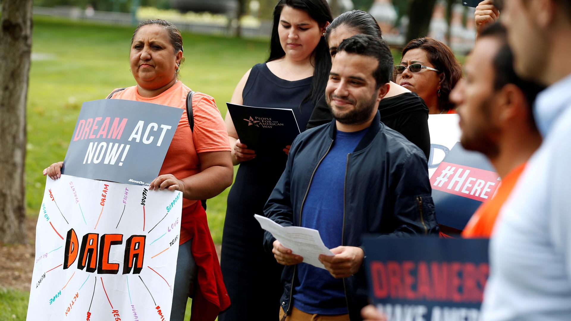 Immigration activists and DACA recipients hold placards saying "Deam Act Now!" and "DACA."