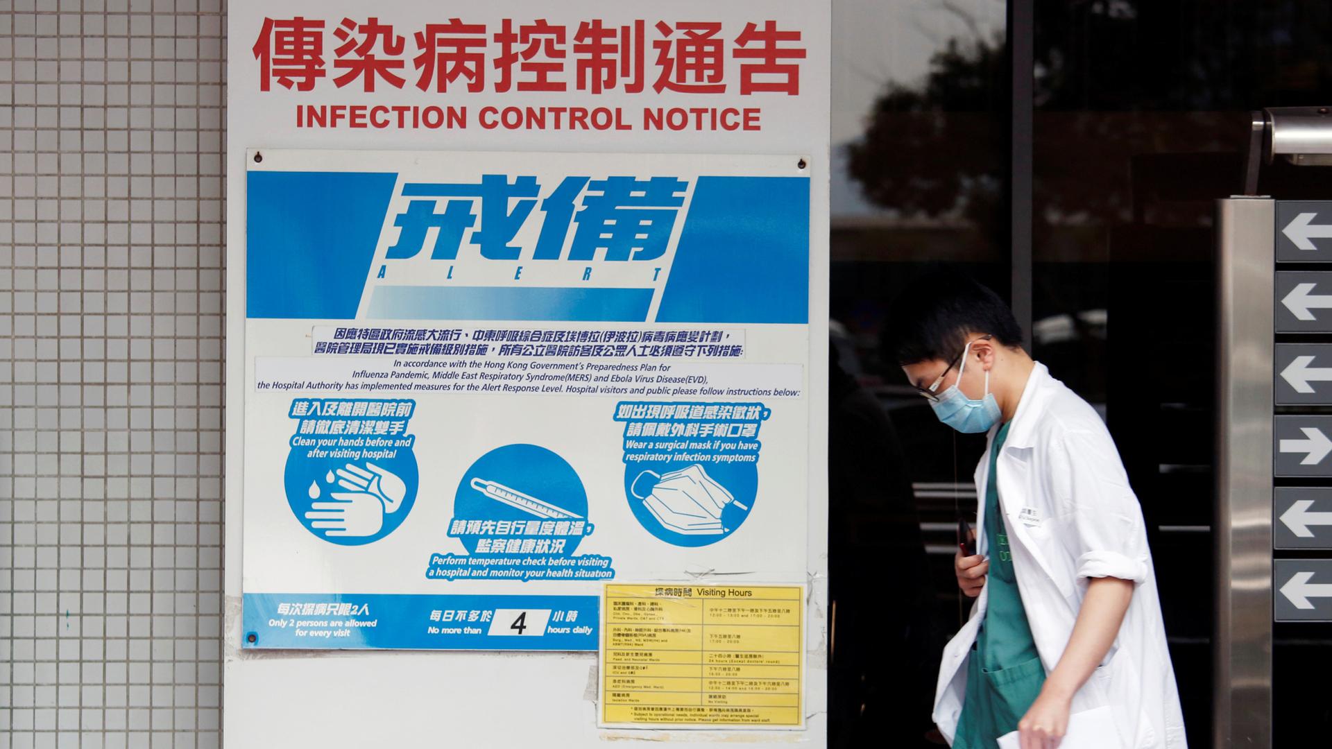 A medical personnel walks past a notice on flu alert at a hospital Hong Kong.