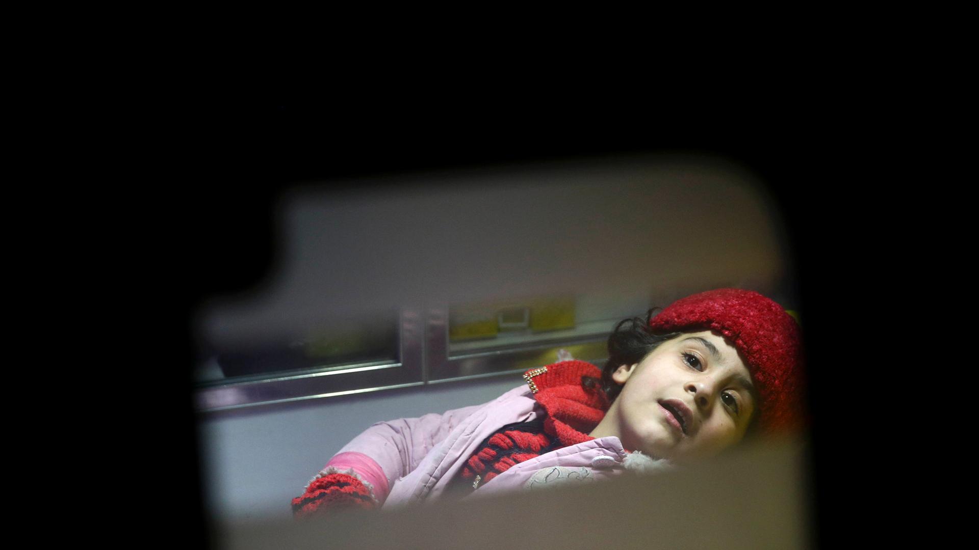 A girl is seen through an ambulance window with in center frame with everything else dark and out of focus.