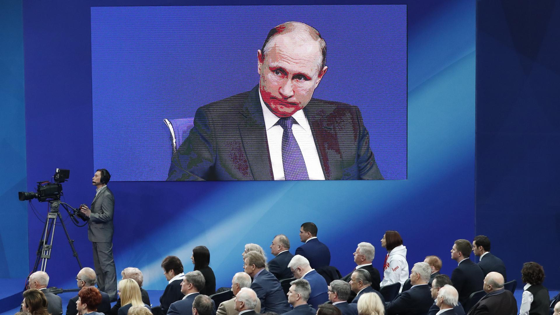 Russian President Vladimir Putin is seen on an electronic screen ahead of the upcoming presidential election in Moscow.