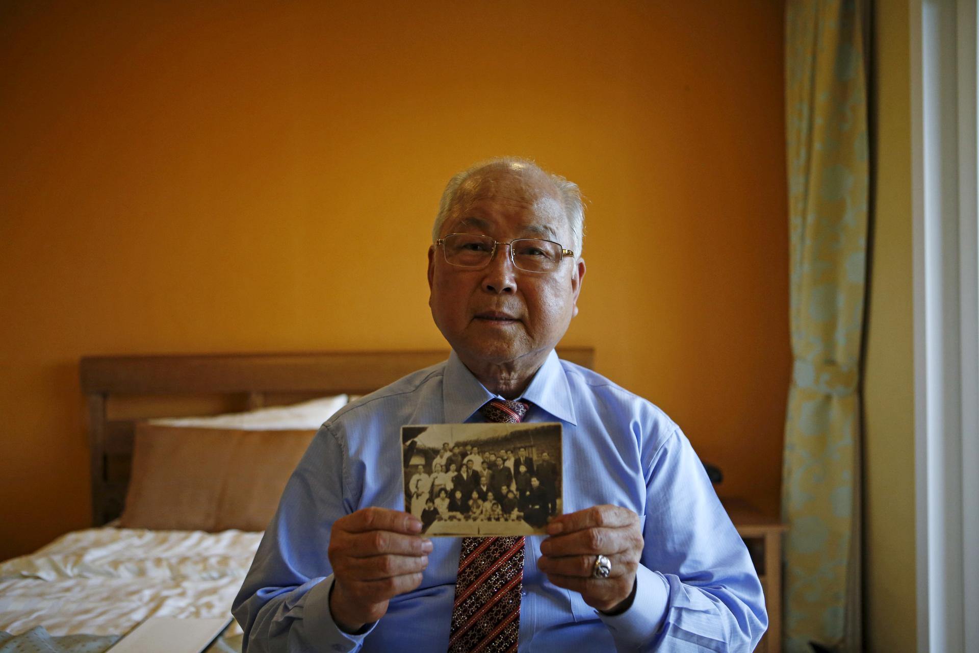 Park Jong-hwan, 80, who is selected as a participant for a reunion, poses for a photograph with an old picture at a hotel used as a waiting place in Sokcho, South Korea, October 19, 2015.