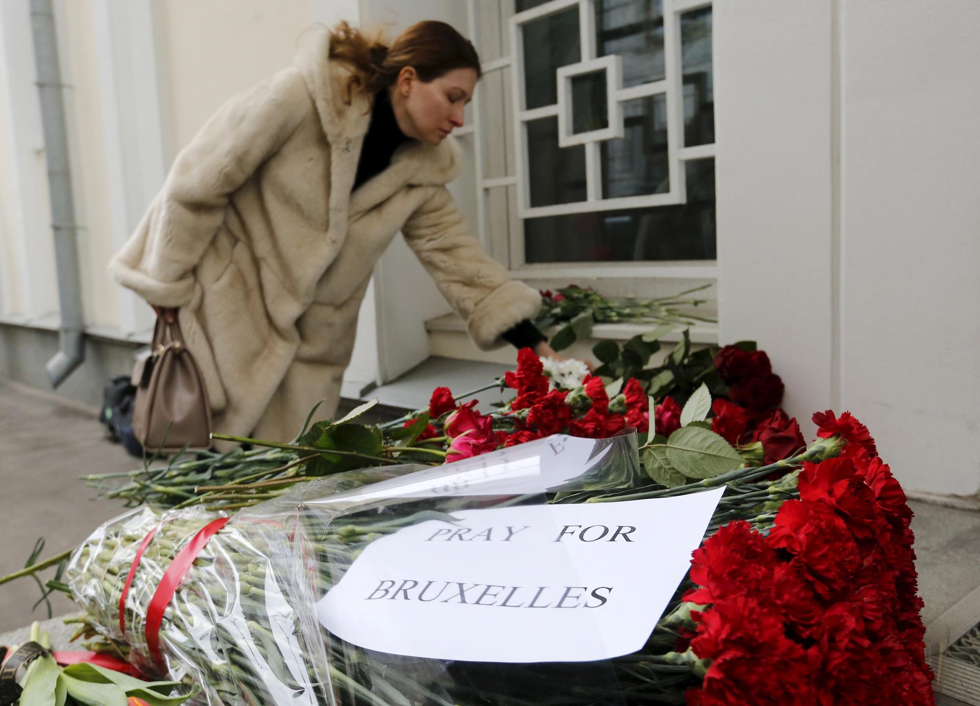 A woman places flowers for the victims of the Brussels attacks, in front of the Belgian embassy in Moscow, Russia,