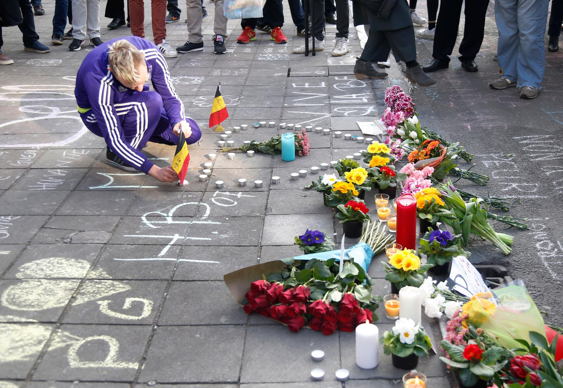 A man places a Belgian flag on a memorial in Brussels following bomb attacks s in Brussels, Belgium,