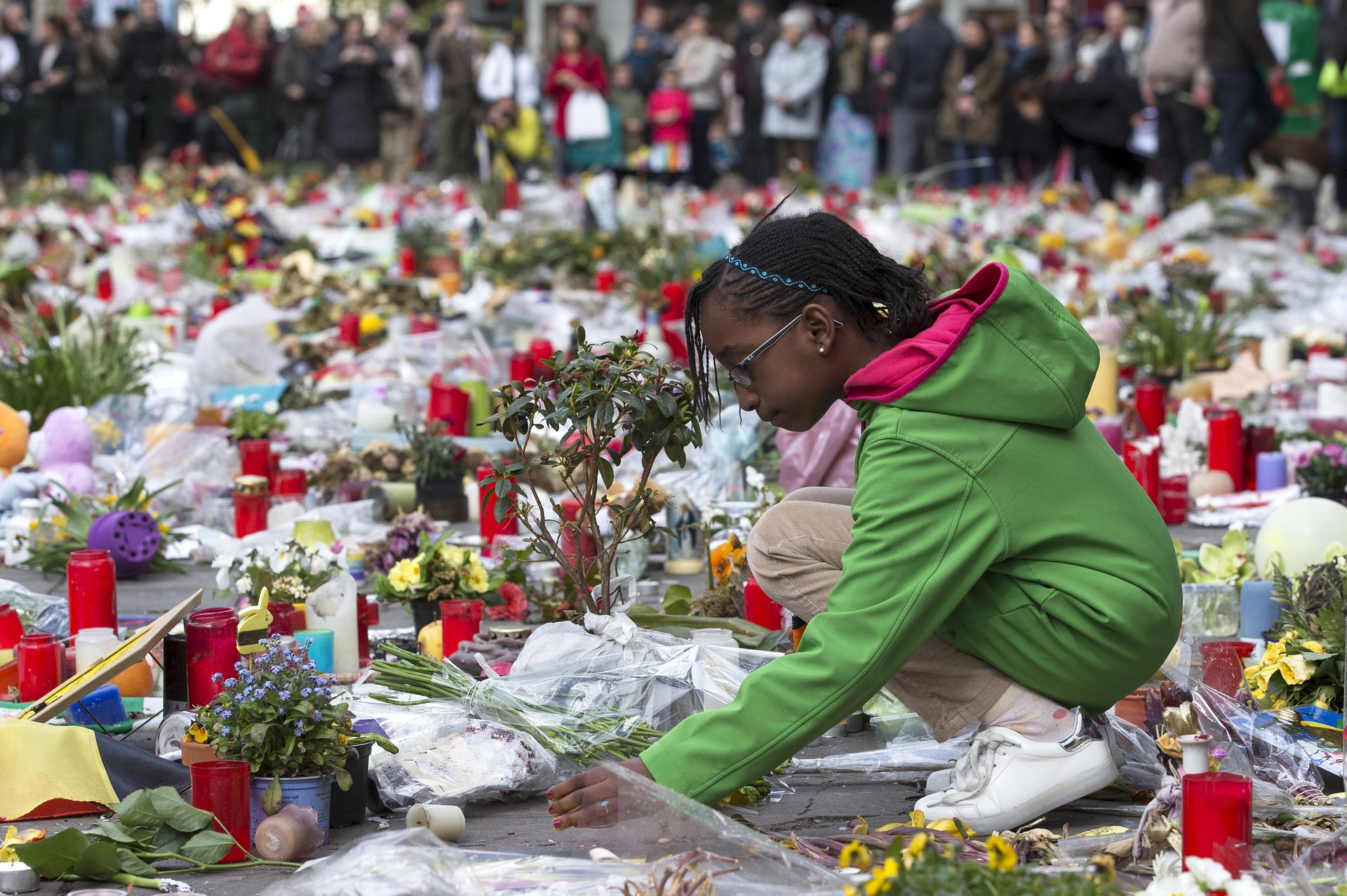 A girl lays a flower on a street memorial during a rally called 