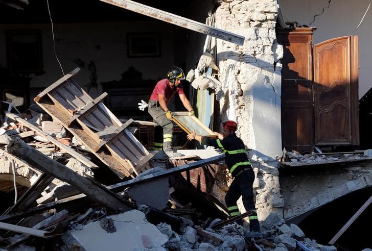 Firefighters remove a painting from a collapsed house following an earthquake in Amatrice, central Italy, August 27, 2016.