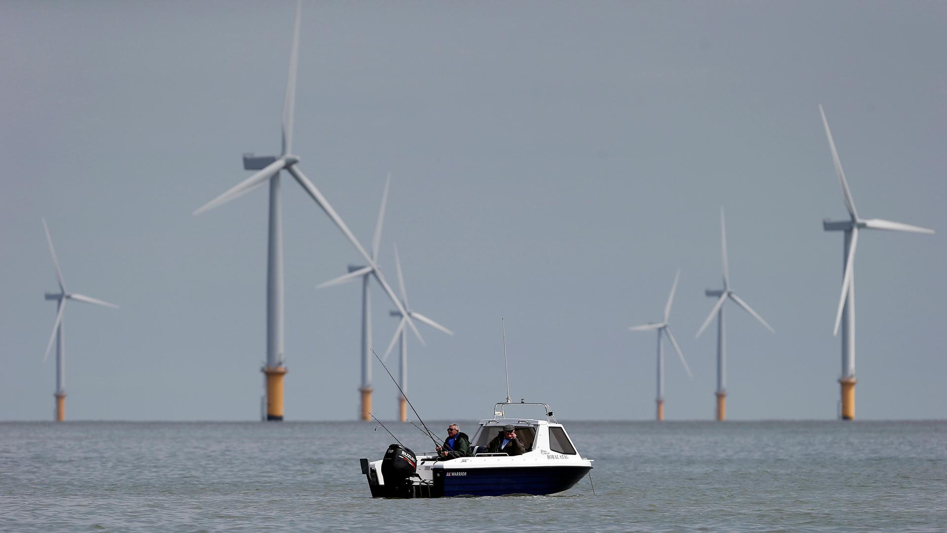 Two fishermen sit in their boat at the Gunfleet Sands Offshore Wind Farm near Clacton-on-Sea, Britain.