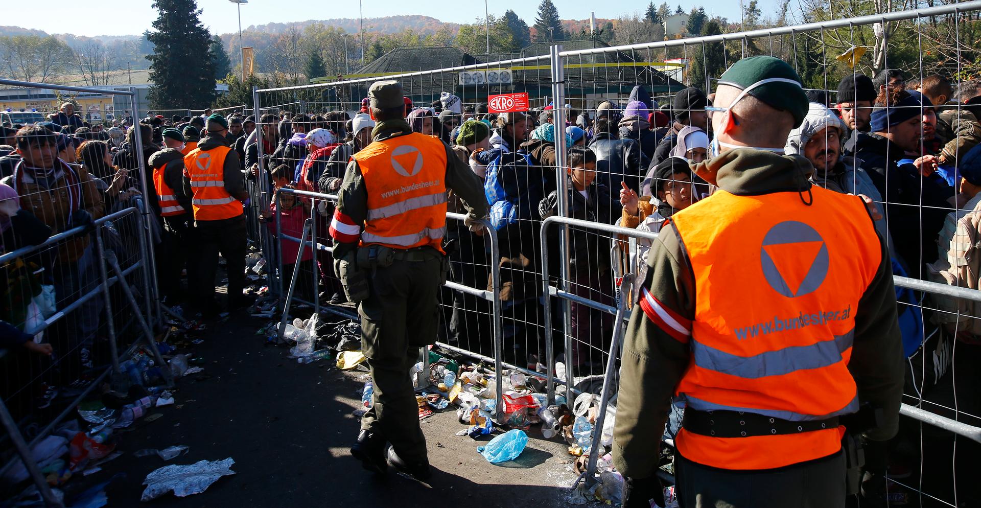 Austrian army soldiers observe migrants as they wait to cross the border from the village of Sentilj, Slovenia into Spielfeld, Austria, Nov. 2, 2015.