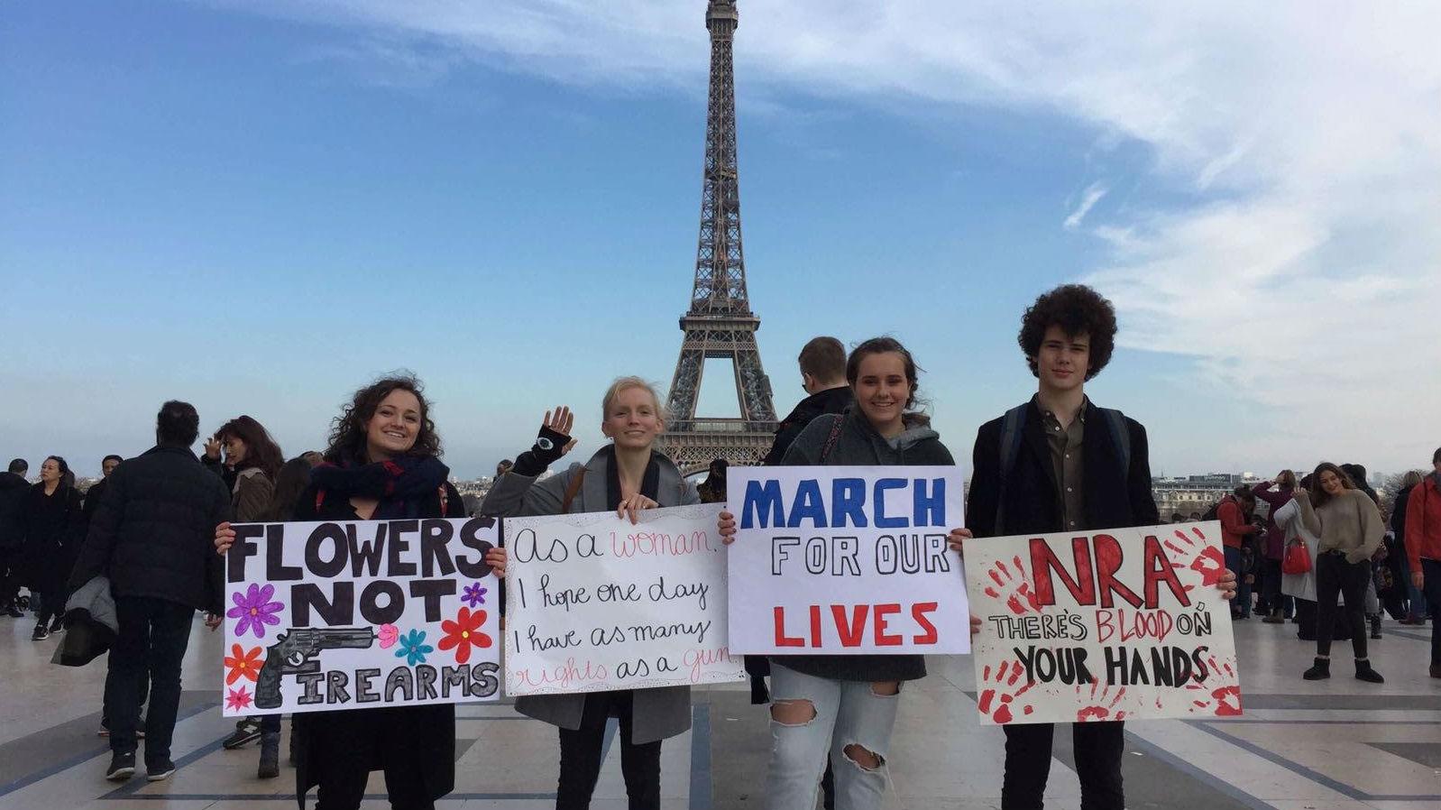 American and French students hold signs in front of the Eiffel Tower in Paris in support of March for Our Lives.