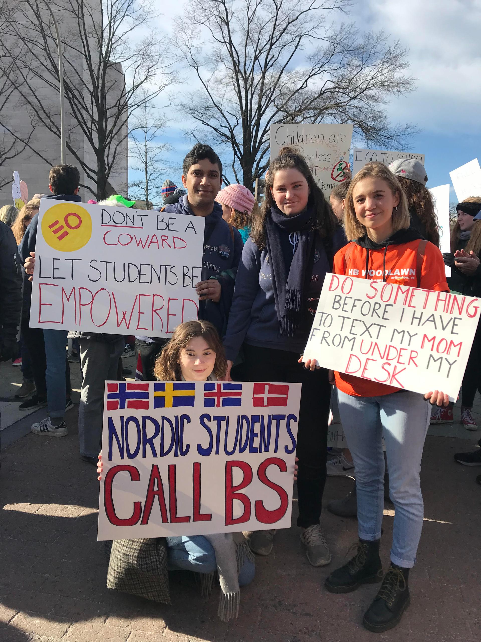 Four students, three who are from Norway, hold signs reading 