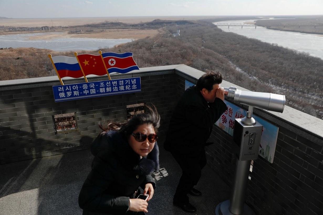 A tourist uses binoculars to look across to North Korea from a tower built on the Chinese side
