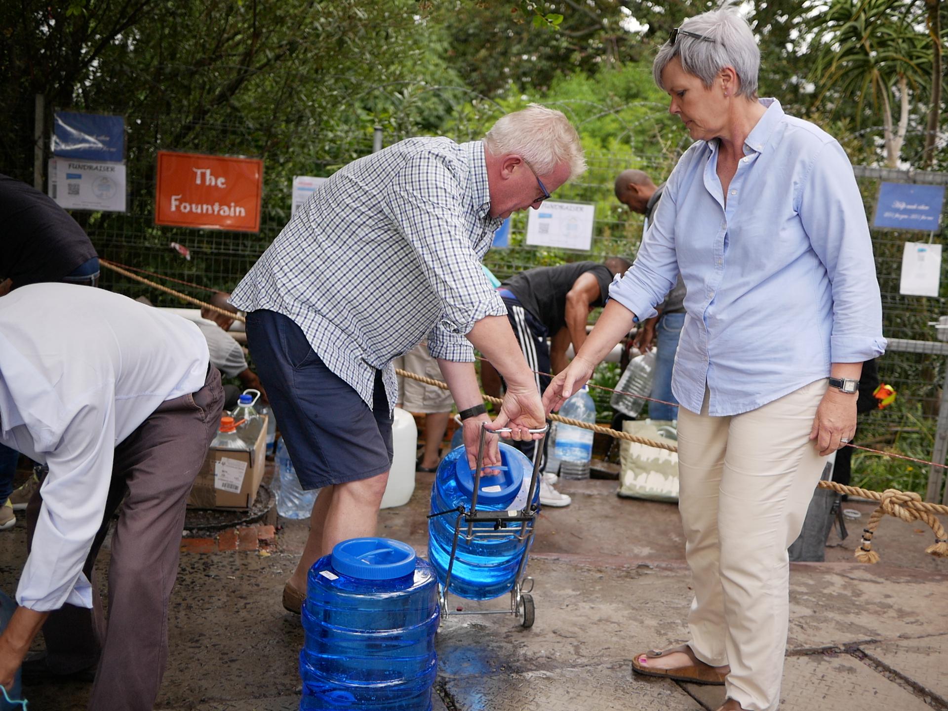 Sabine and Nils Heckscher hold jerricans to collect water at a natural spring in Newlands, Cape Town.