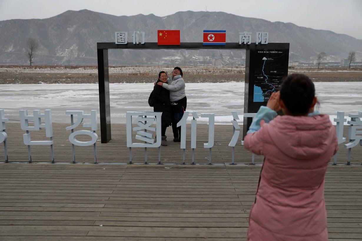 People have a picture taken of themselves with North Korea in the background, in Tumen, China.