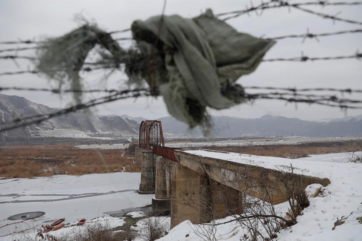 A piece of clothing is used to make a gap in barbed wire