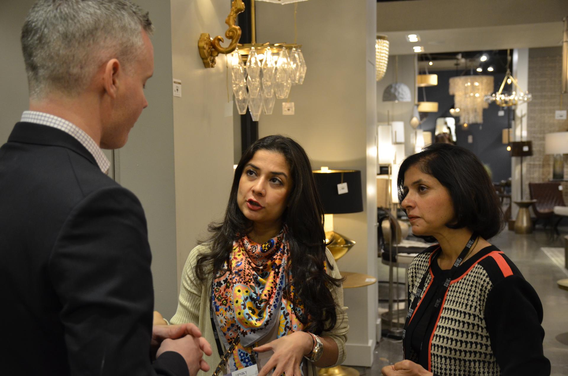 Approximately 10 percent of the nearly 80,000 visitors to The High Point Market are international. Indian interior designers Smita Prakash (left) and Divya Jain speak with Henry Hart, international sales manager with Arteriors.