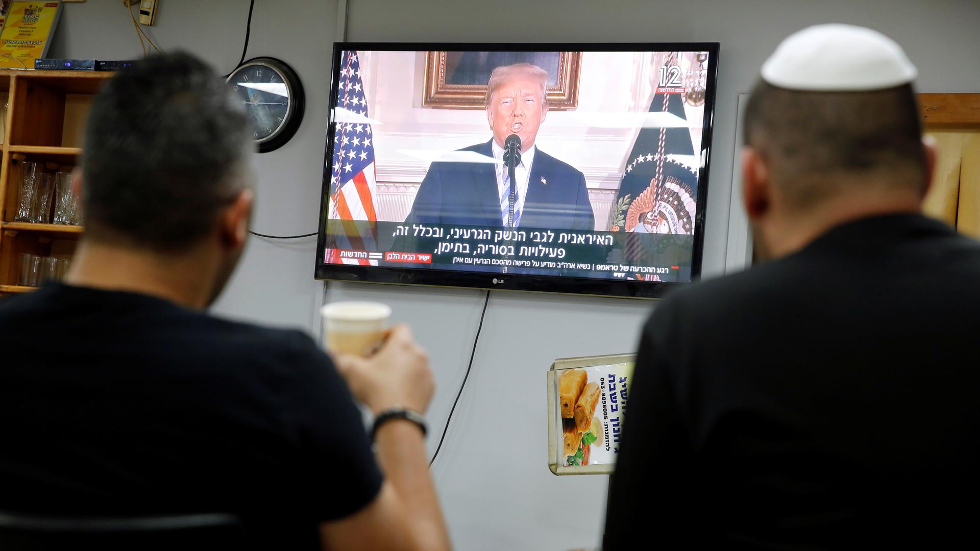 Israelis sit in a coffee shop, watching a television broadcast of US President Donald Trump speaking at the White House, May 8, 2018.