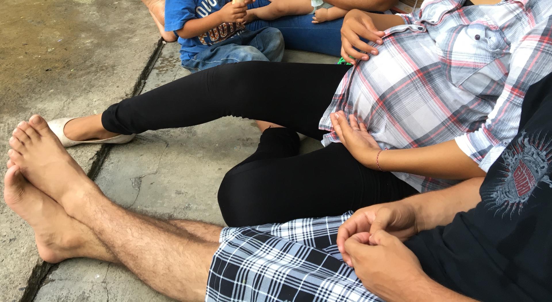 Bodies and feet of two young people, one pregnant