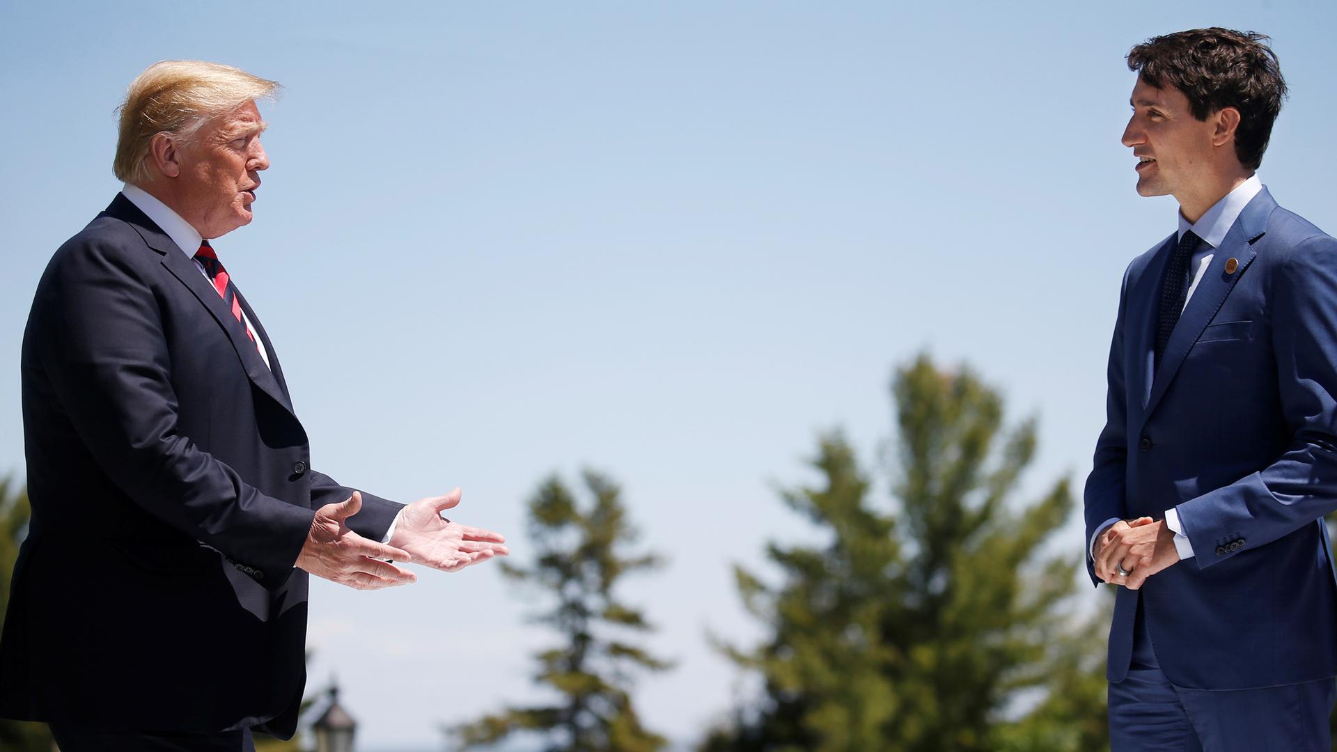 US President Donald Trump is seen left with his hands out reaching toward Canada's Prime Minister Justin Trudeau on the right of the frame.