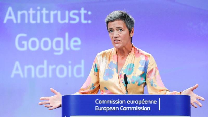 European Competition Commissioner Margrethe Vestager stands at a podium with a screen behind her reading "Antitrust: Google Android."