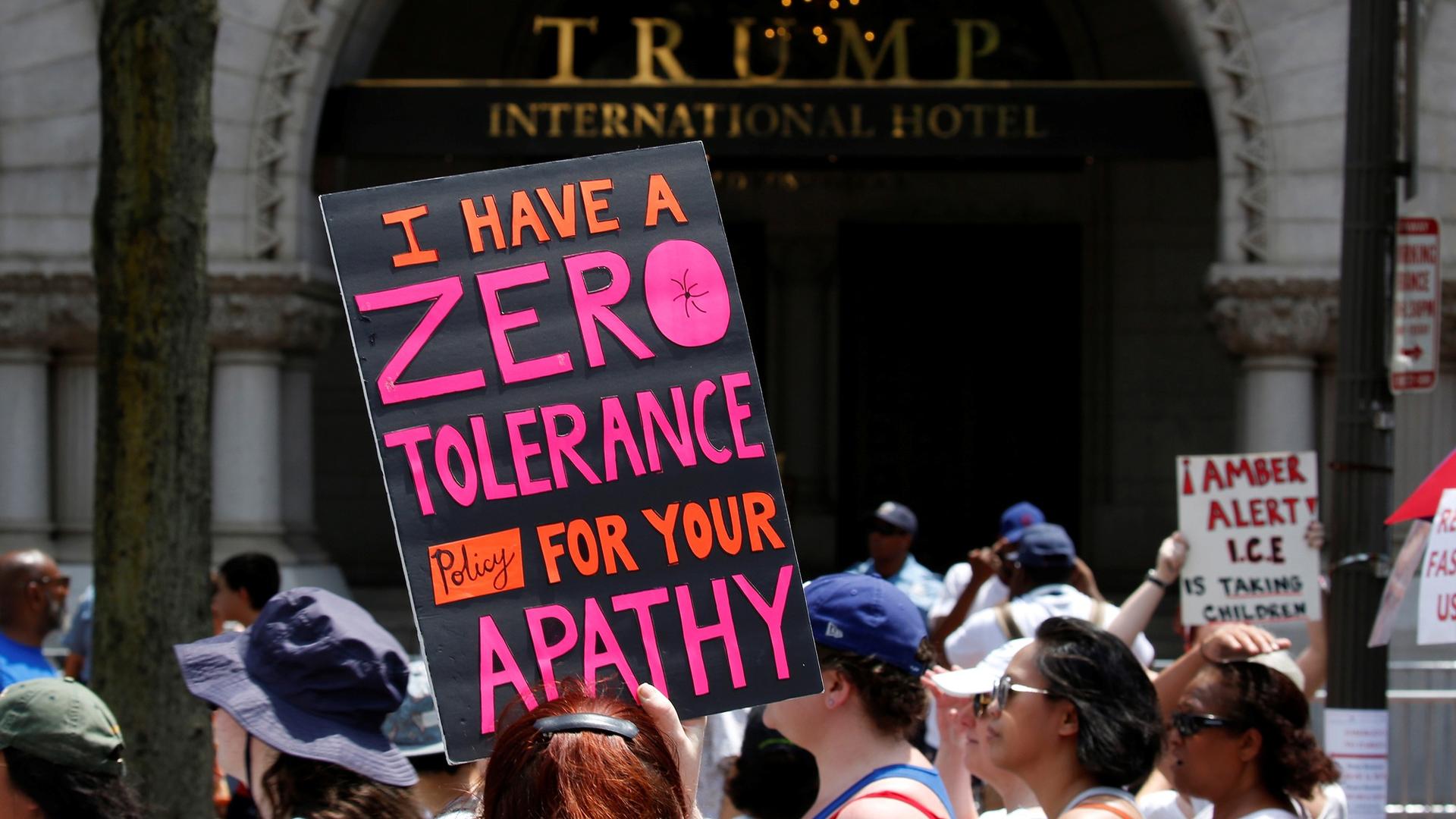 An immigration activist is shown carrying a sign that reads, "I have zero tolerance policy for your apathy," outside the Trump International Hotel in Washington, DC, June 30, 2018.