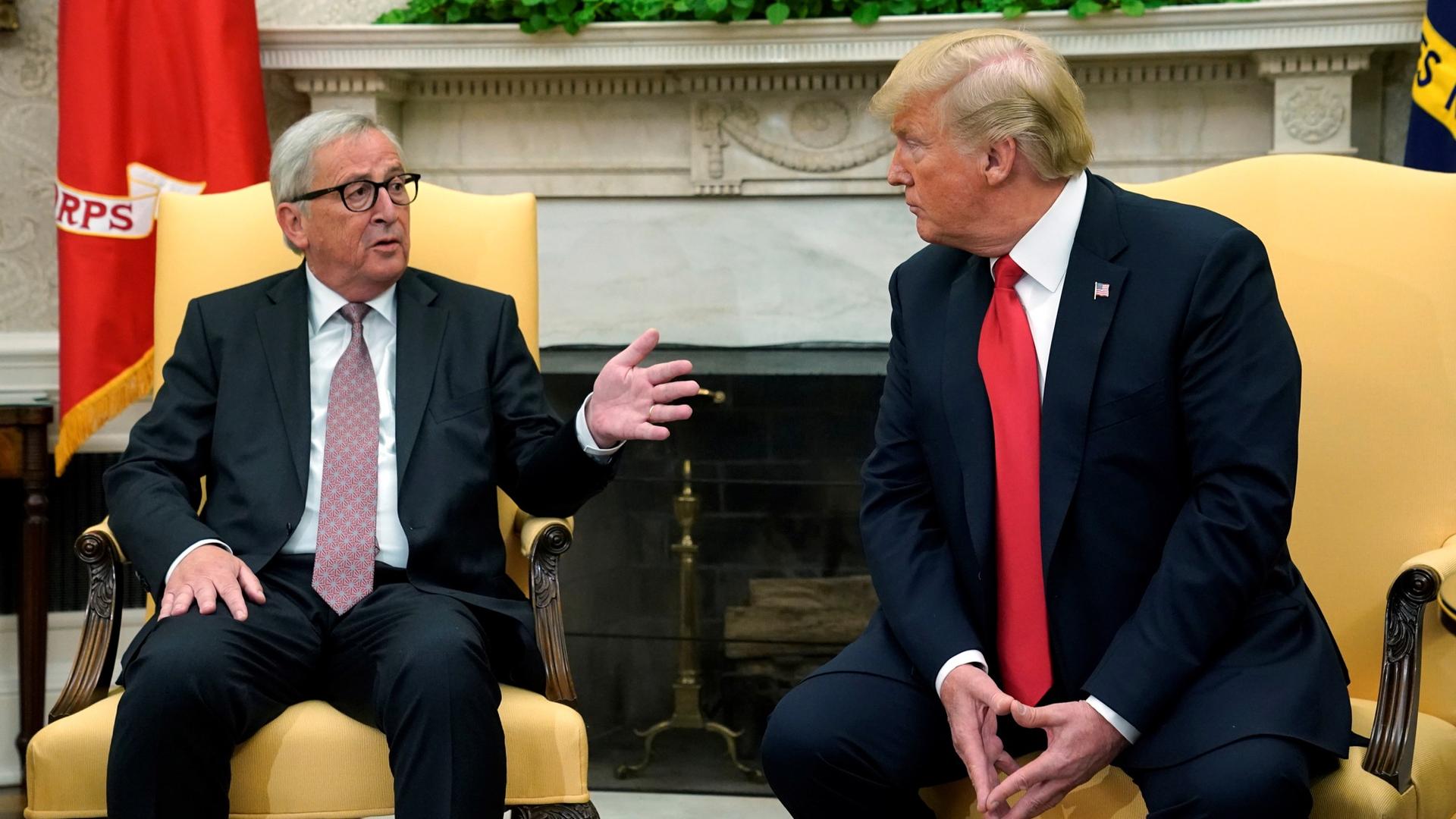 US President Donald Trump sits on the edge of an armchair next to European Commission President Jean-Claude Juncker who is also seated.