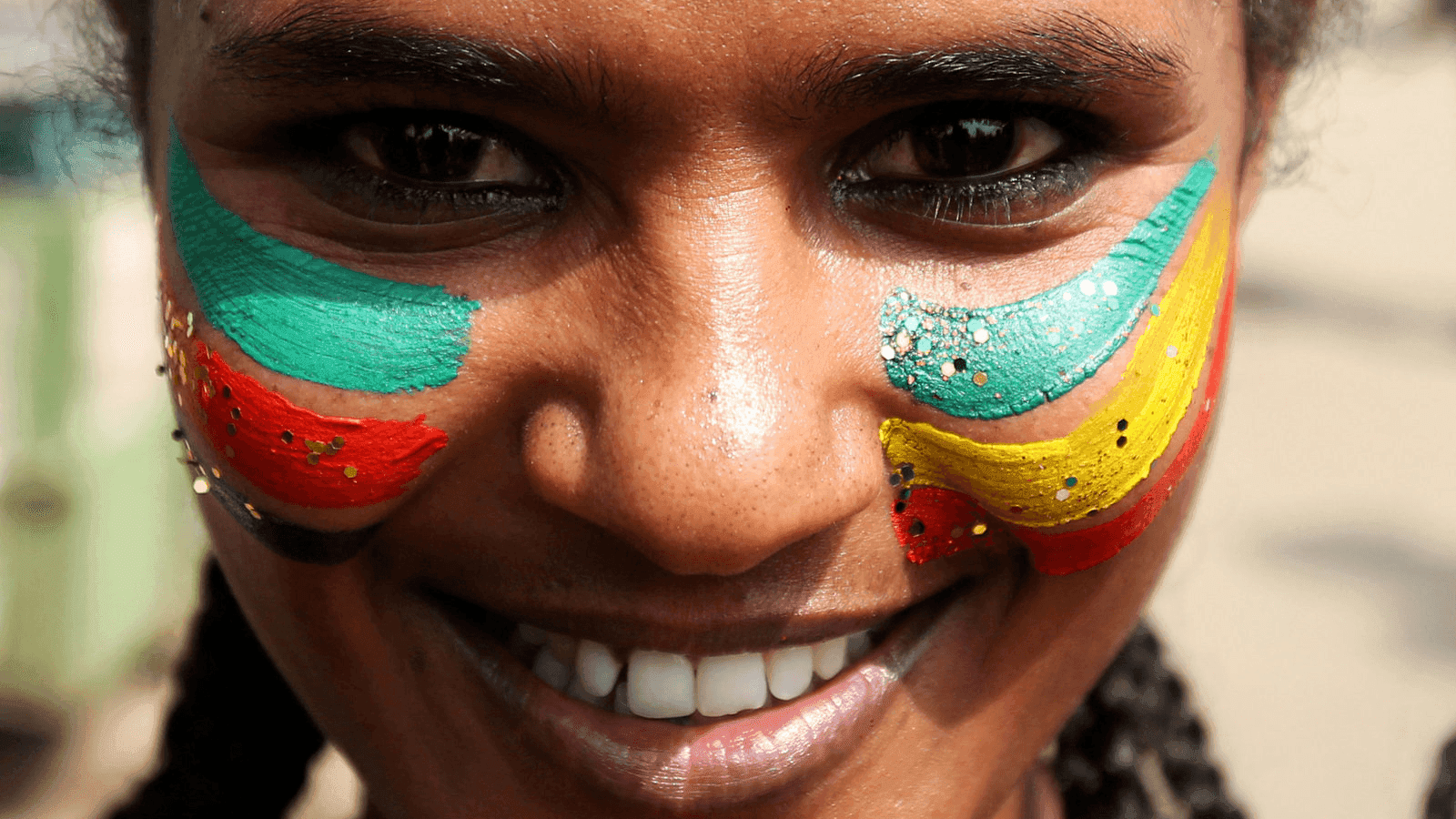 a woman's face painted with ethiopian and eritrean flags