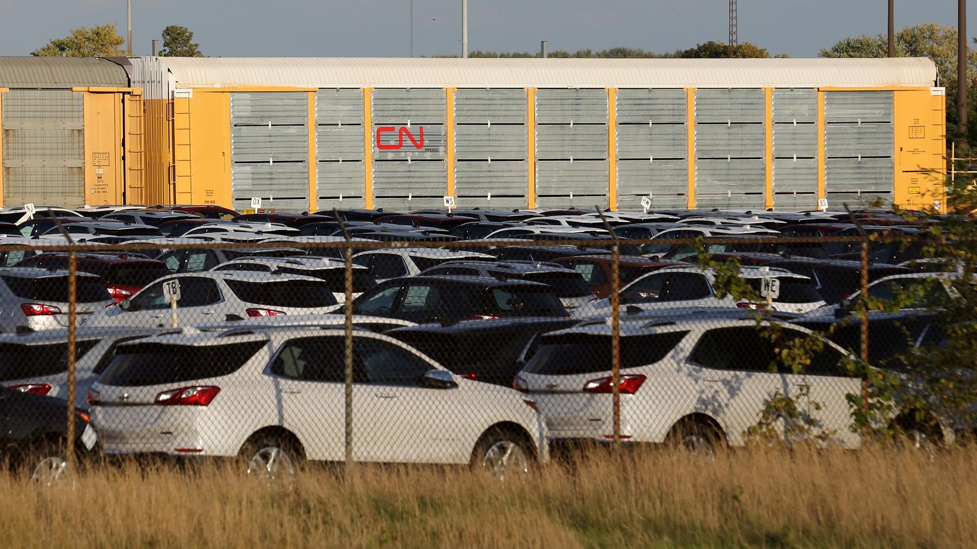 Chevrolet Equinox SUVs are shown parked in a fenced in area with CN Rail cars in tbe background.