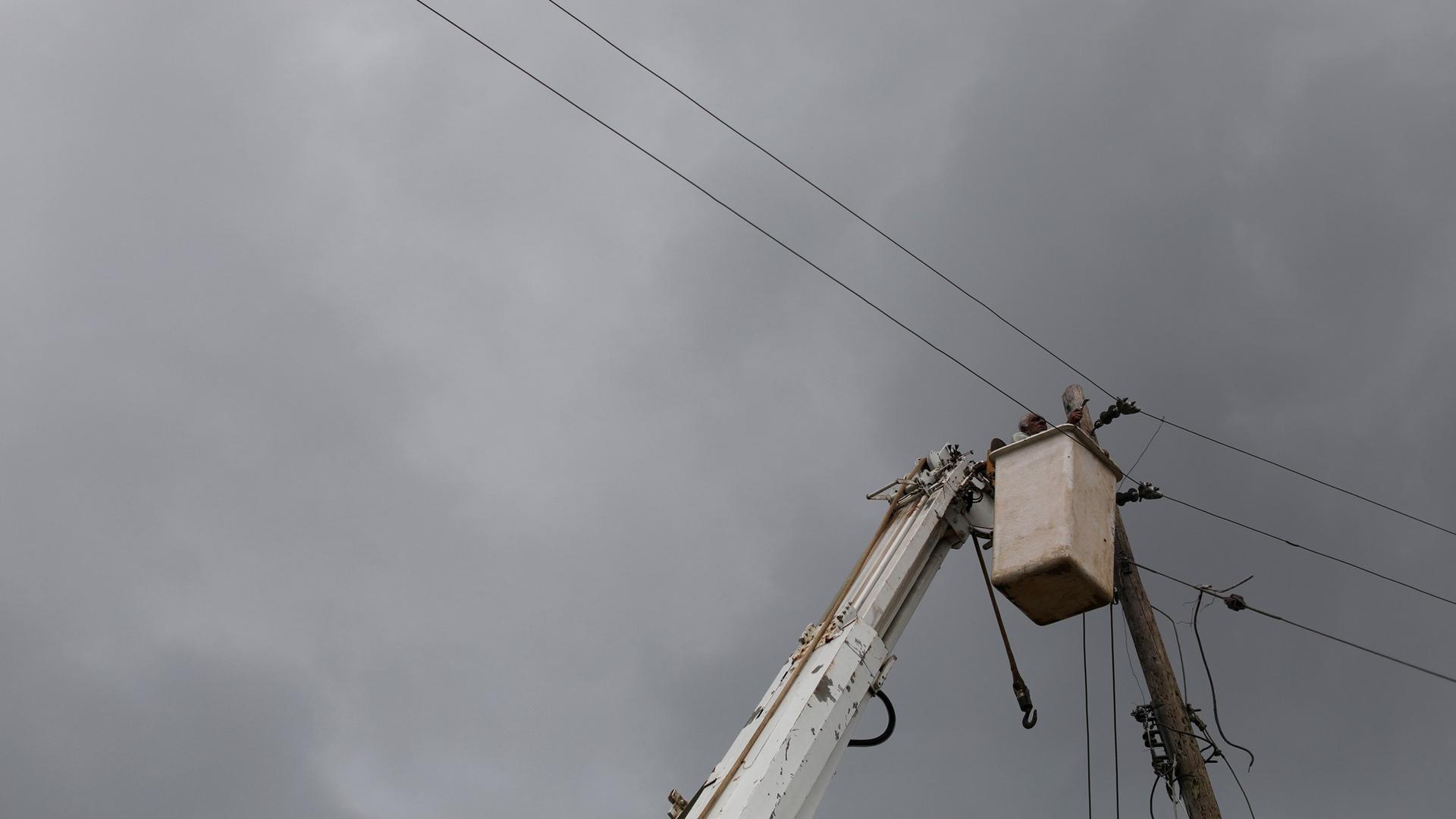 A resident Puerto Rico works from a mechanical lift at the top of an electrical pole.