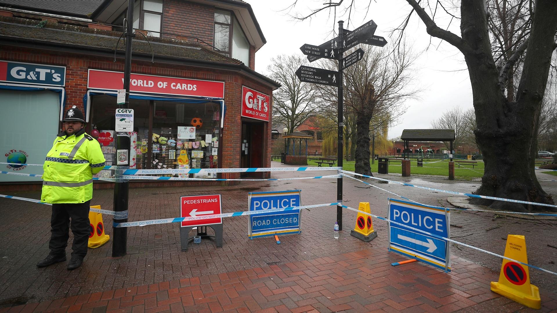 A police officer is shown standing to the left of the photograph, wearing a fluorescent jacket guards a cordoned off area where former Russian intelligence officer Sergei Skripal and his daughter Yulia were found poisoned.