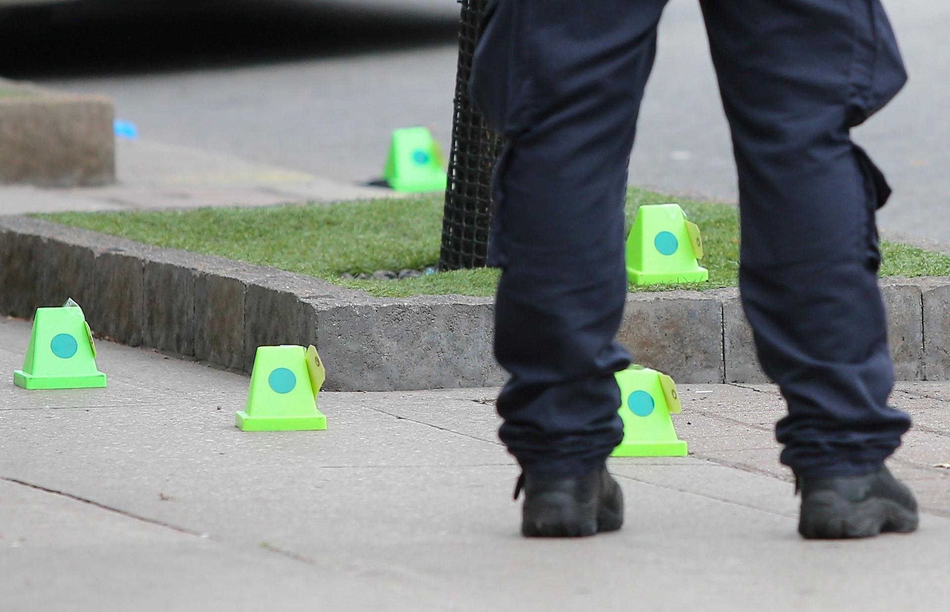 A police officer stands near evidence markers while investigating a mass shooting on Danforth Avenue in Toronto, Canada.