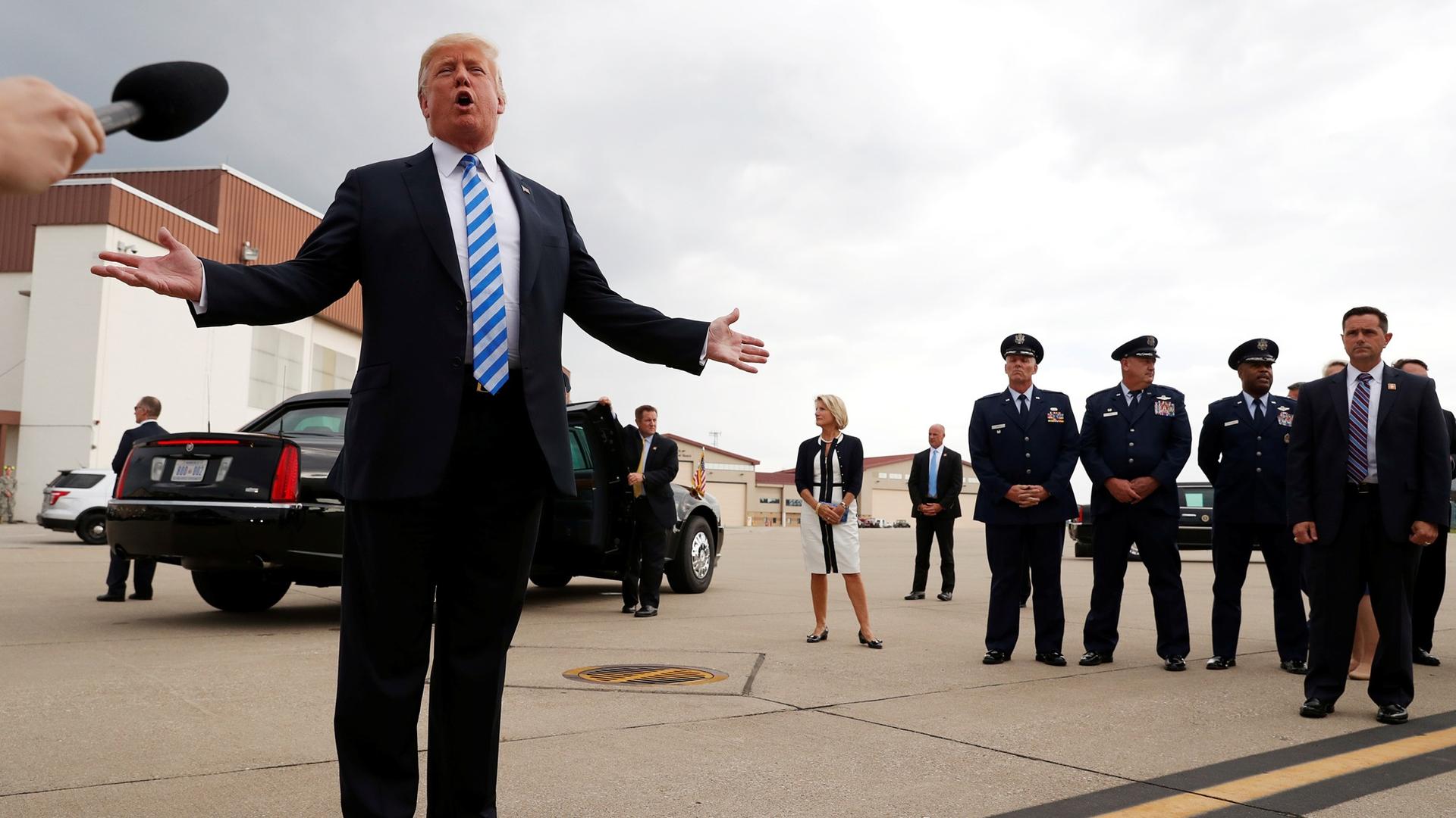 President Donald Trump speaks to the news media with his arms outspread on the airport tarmac in Charleston, West Virginia, August 21, 2018.