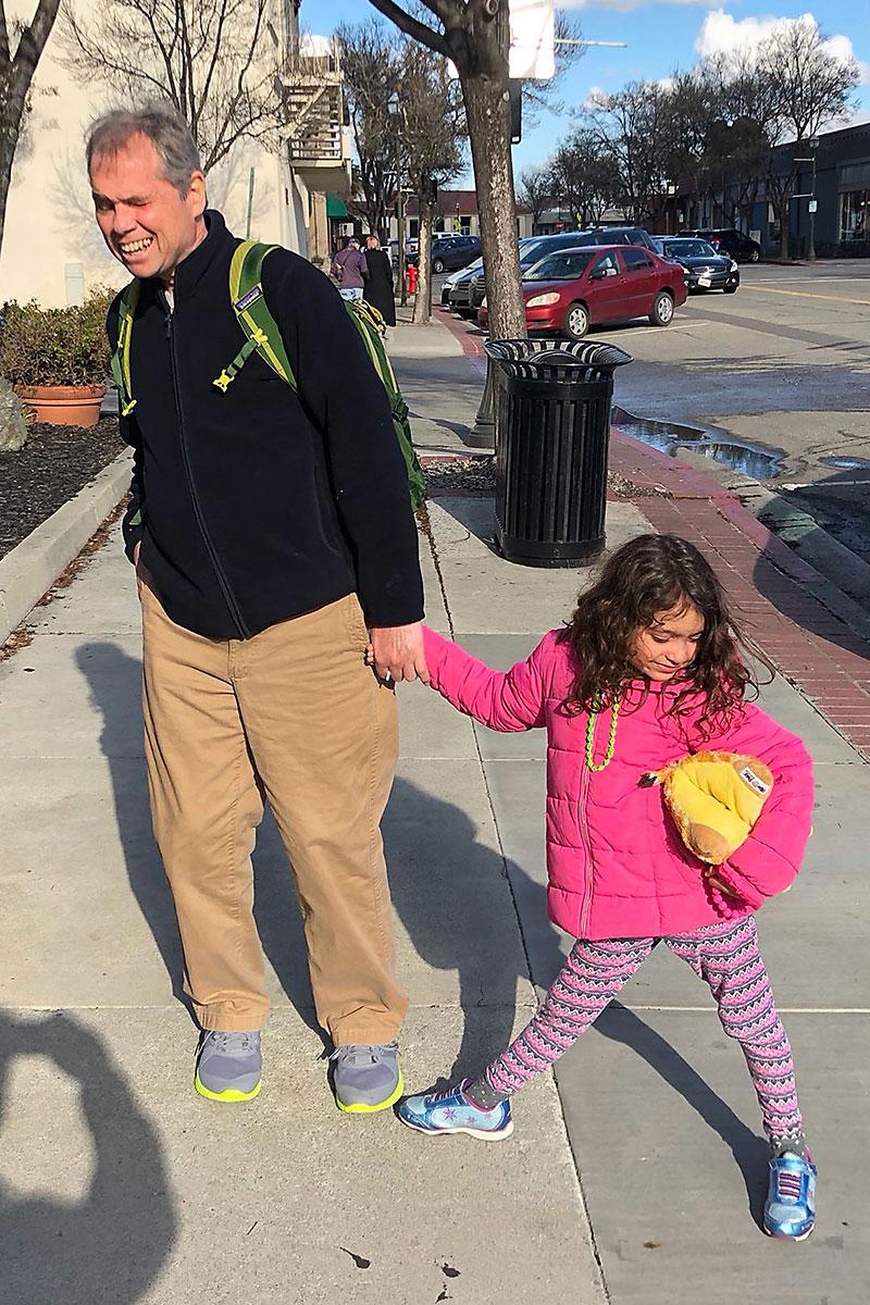 A man holds a young girl's hand as they pose for a photo