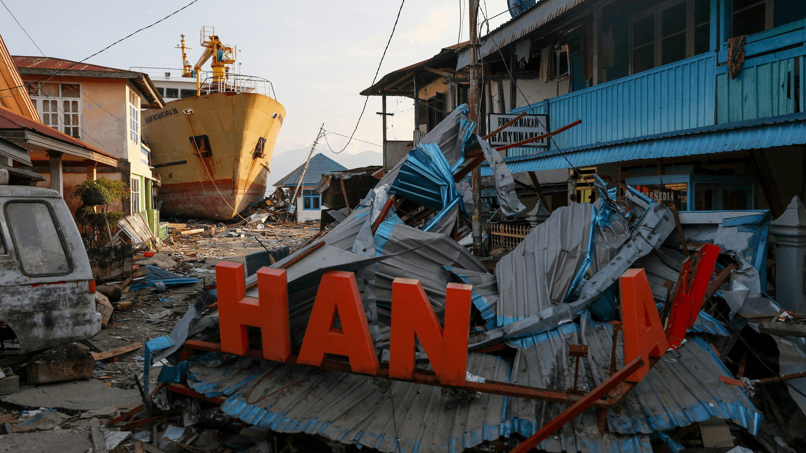 a ship and other debris on a beach in indonesia after a tsunami