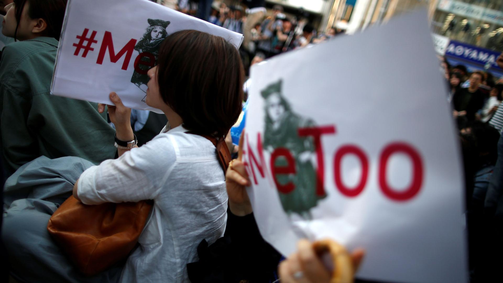 Protesters are shown holding white placards with red lettering reading "#MeToo" during a rally against sexual harassment in Tokyo, Japan.