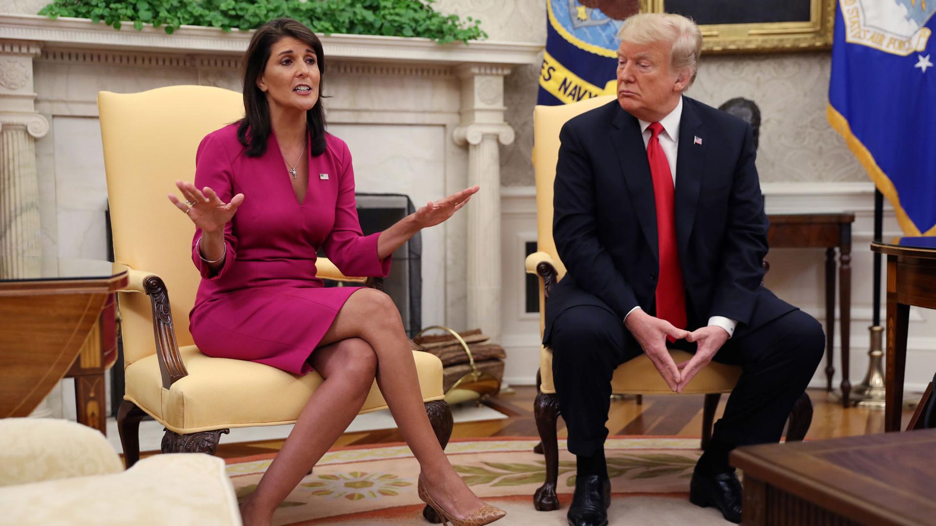 Outgoing US Ambassador to the United Nations Nikki Haley is shown in a pink dress sitting next to President Donald Trump wearing a dark blue suit and red tie.