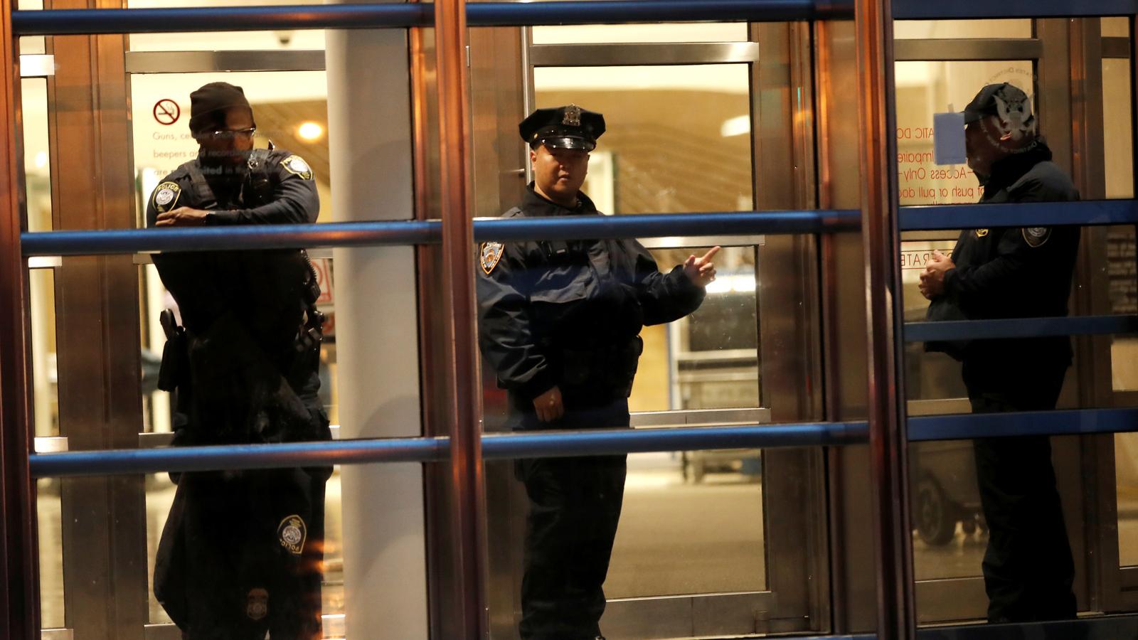 Three police stand inside the courthouse in Brooklyn