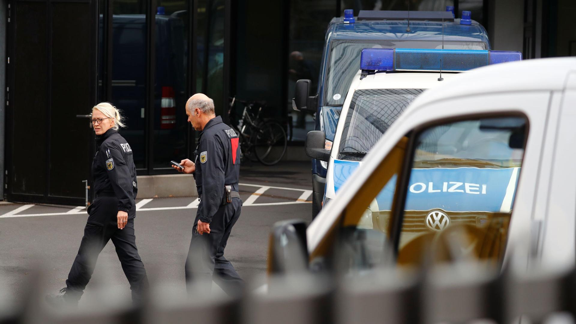 Two police officers are seen walking past police vehicles in front of Deutsche Bank headquarters in Frankfurt, Germany, Nov. 29, 2018.